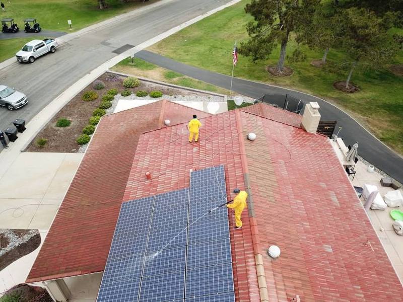 Crew washing solar panels and a tile roof